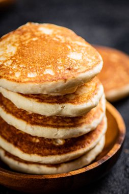 A pile of homemade pancakes in a plate on the table. On a black background. High quality photo