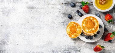 Pancakes in a plate with berries and honey. On a gray background. High quality photo