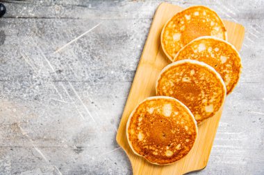 Homemade pancakes on a wooden cutting board. On a gray background. High quality photo