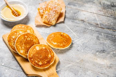 Pancakes on a cutting board with honey. On a gray background. High quality photo