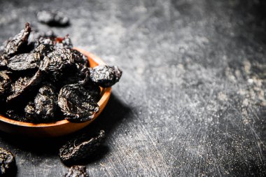Prunes in a wooden plate on the table. On a black background. High quality photo