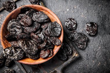 Prunes in a plate on a cutting board. On a black background. High quality photo