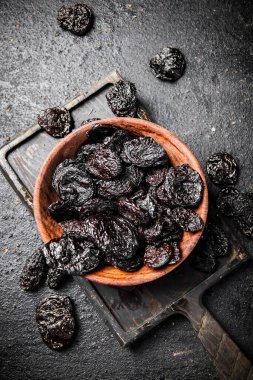 Prunes in a plate on a cutting board. On a black background. High quality photo