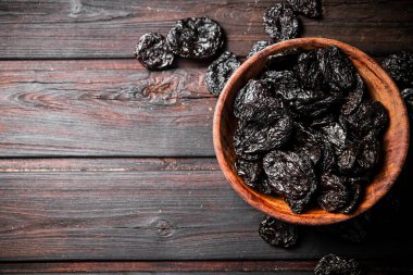 Prunes in a plate on a wooden background. Top view. High quality photo