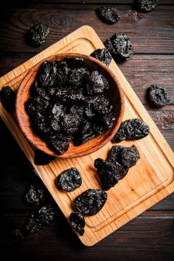 Prunes on a wooden cutting board. On a dark wooden background. High quality photo