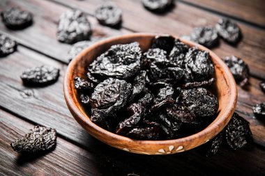 Prunes wooden plate on the table. On a wooden background. High quality photo