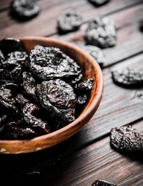 Prunes wooden plate on the table. On a wooden background. High quality photo