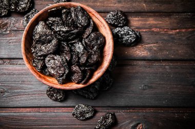 Prunes in a plate on a wooden background. Top view. High quality photo