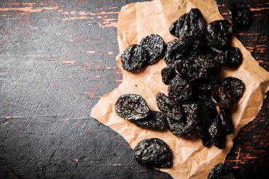 Prunes on paper on the table. Against a dark background. High quality photo