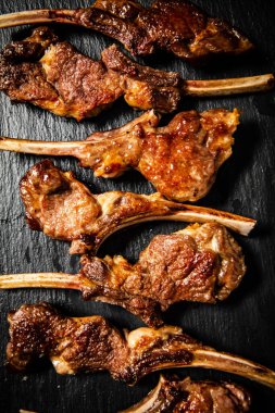 Fragrant grilled lamb rack on a stone board. On a black background. High quality photo