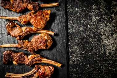 Fragrant grilled lamb rack on a stone board. On a black background. High quality photo