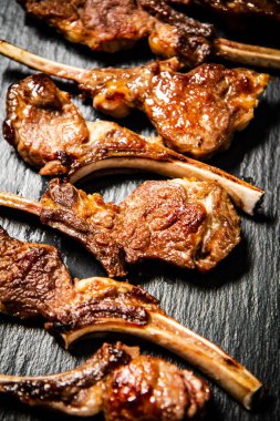 Fragrant grilled lamb rack on a stone board. On a black background. High quality photo