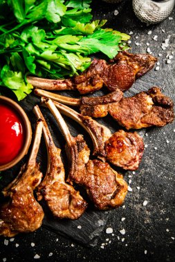 Rack of lamb with tomato sauce and parsley on the table. On a black background. High quality photo
