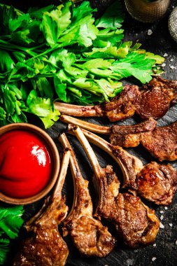 Rack of lamb with tomato sauce and parsley on the table. On a black background. High quality photo
