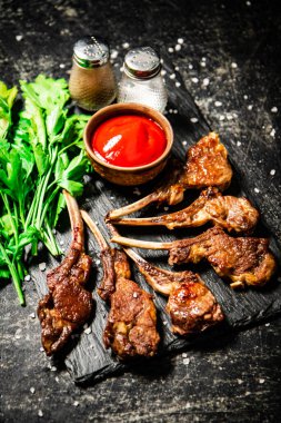 Rack of lamb with tomato sauce and parsley on the table. On a black background. High quality photo