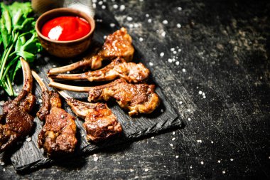 Rack of lamb with tomato sauce and parsley on the table. On a black background. High quality photo