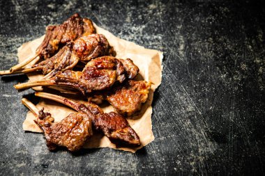 A rack of grilled lamb on paper on the table. On a black background. High quality photo