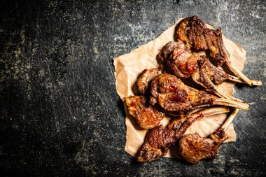 A rack of grilled lamb on paper on the table. On a black background. High quality photo