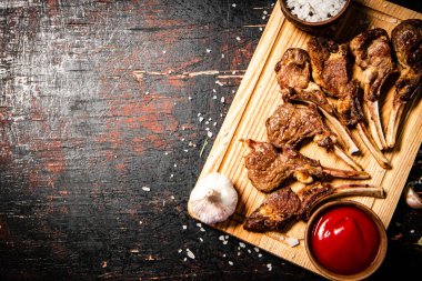Grilled rack lamb with spices and tomato sauce. Against a dark background. High quality photo
