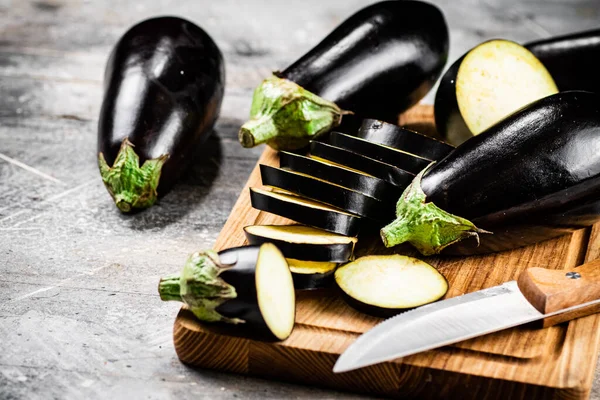 Cut into pieces of ripe eggplant on a wooden cutting board. On a gray background. High quality photo