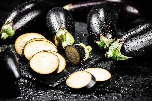 Pieces of ripe eggplant on a stone board. On a black background. High quality photo