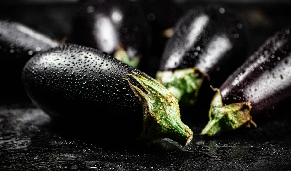 stock image Fresh wet eggplant on the table. On a black background. High quality photo