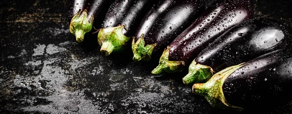 Ripe eggplant with droplets of water. On a black background. High quality photo