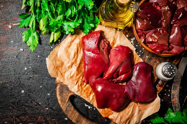 stock image Pieces of raw liver with spices, oil and herbs. Against a dark background. High quality photo