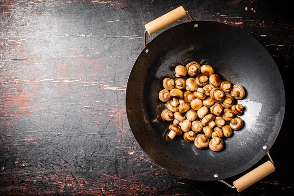 Small fried mushrooms in a frying pan. Against a dark background. High quality photo