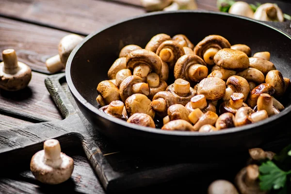 Stock image Fragrant homemade fried mushrooms in a frying pan on a cutting board. On a wooden background. High quality photo