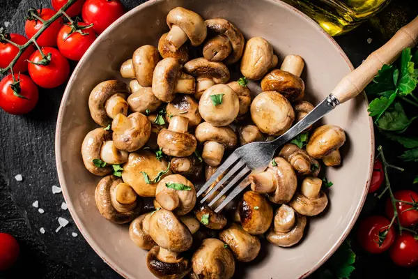 stock image Fried mushrooms in a bowl with cherry tomatoes. On a black background. High quality photo