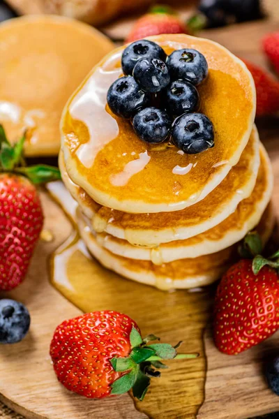 stock image A pile of pancakes with fresh berries and honey on the table. On a wooden background. High quality photo