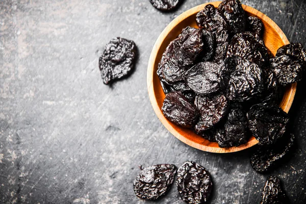 stock image Prunes in a wooden plate on the table. On a black background. High quality photo