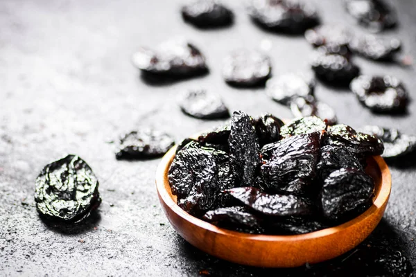 stock image Prunes in a wooden plate on the table. On a black background. High quality photo