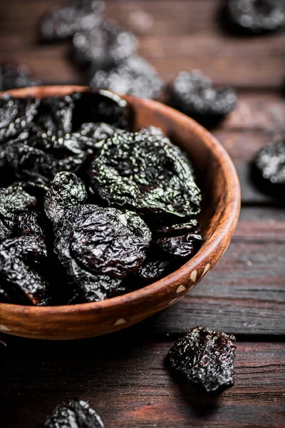 Prunes wooden plate on the table. On a wooden background. High quality photo