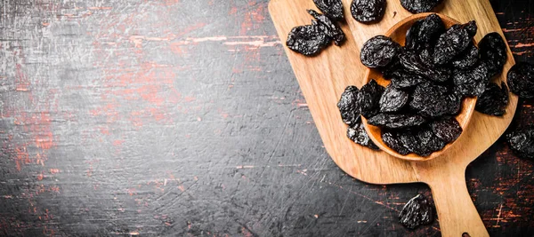 Prunes in a plate on a wooden cutting board. Against a dark background. High quality photo