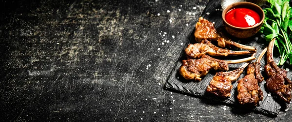 stock image Rack of lamb with tomato sauce and parsley on the table. On a black background. High quality photo