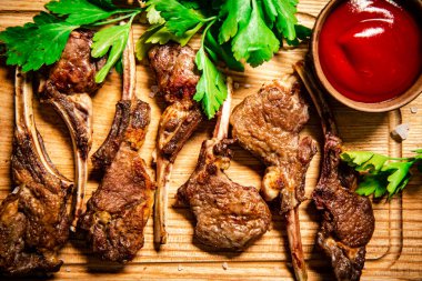 Grilled lamb rack with parsley and tomato sauce. On a wooden background. High quality photo