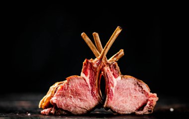 A delicious rack of grilled lamb on the table. On a black background. High quality photo