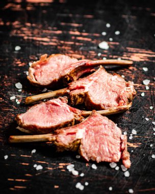 Rack grilled lamb with salt on the table. Against a dark background. High quality photo