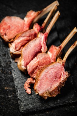 Rack lamb grill on a stone board. On a black background. High quality photo