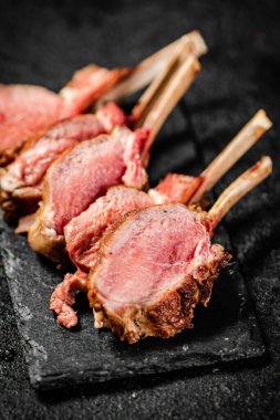Rack lamb grill on a stone board. On a black background. High quality photo