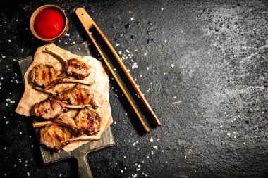 Grilled rack lamb with tomato sauce. On a black background. High quality photo