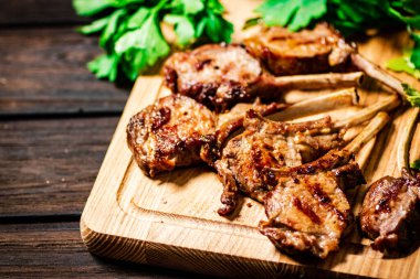 Delicious grilled lamb rack on a cutting board with parsley. On a wooden background. High quality photo