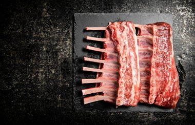 Raw rack of lamb on a stone board. On a black background. High quality photo