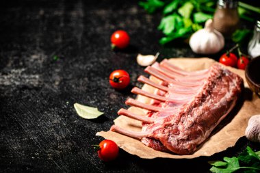 Raw rack of lamb with parsley and tomatoes. On a black background. High quality photo