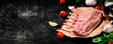 Raw rack of lamb with parsley and tomatoes. On a black background. High quality photo
