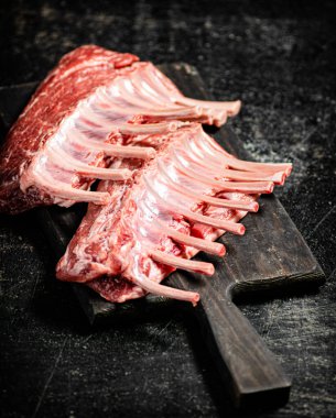 Raw rack of lamb on a cutting board on the table. On a black background. High quality photo