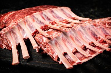 Raw rack of lamb on a cutting board on the table. On a black background. High quality photo