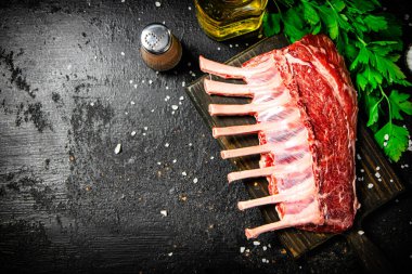 Raw rack of lamb with parsley and oil. On a black background. High quality photo